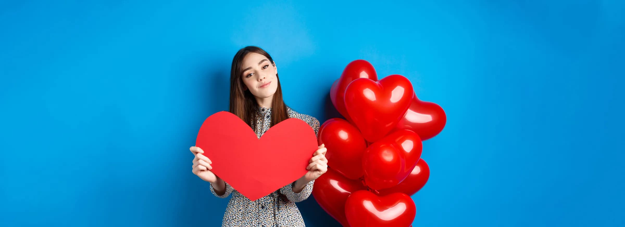 Mujer sosteniendo un corazón rojo entre globos — contacta a Regalitos con Amor en Medellín